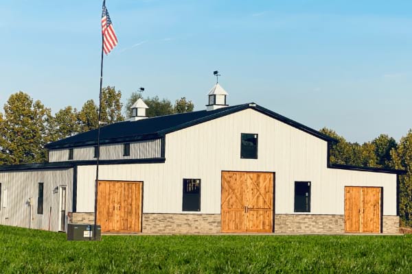 Blue Steel Manufacturing Shop home building with cupolas and black roof and wooden doors